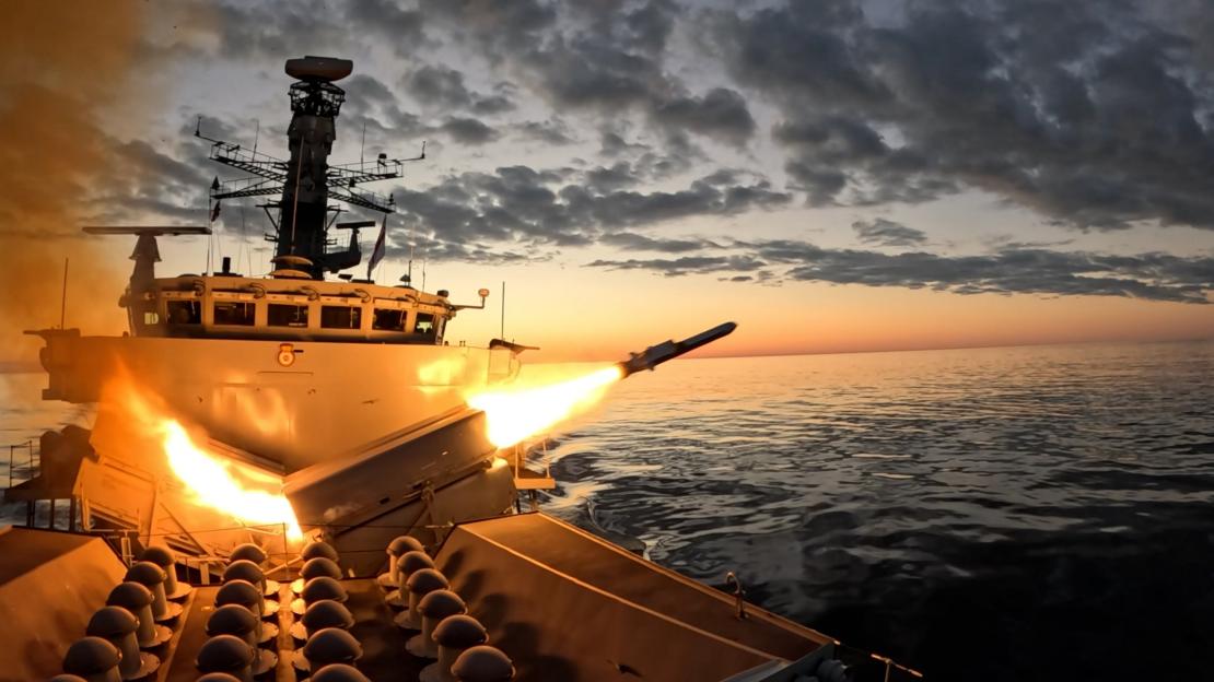 A Royal Navy frigate firing a Naval Strike Missile at sea during sunset.
