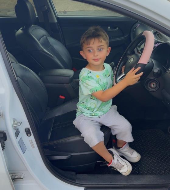 Toddler sitting in driver's seat of car.
