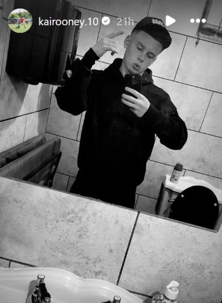 Black and white photo of Kai Rooney taking a selfie in a bathroom.