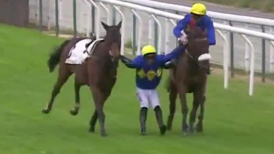 Jockey falling between two horses during a race.