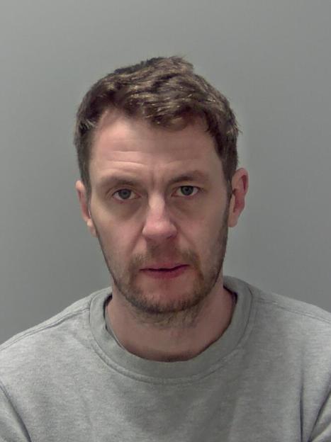 Mugshot of Benjamin Woodrow, a 41-year-old man with light brown hair and a beard, wearing a grey sweatshirt.