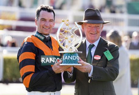 Patrick Mullins and Willie Mullins holding the Randox Grand National trophy.