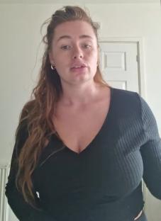 Woman in black top speaking to camera.