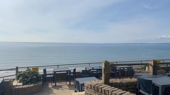 Ocean view from a patio with tables and chairs.