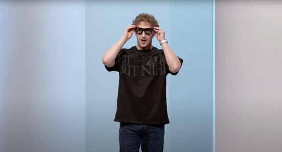 a man wearing glasses and a black t-shirt that says 