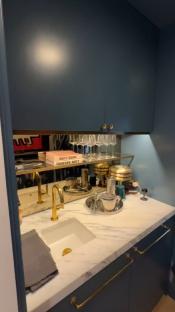 Graham Norton's New York townhouse bar area with marble countertop, brass fixtures, and a sink.