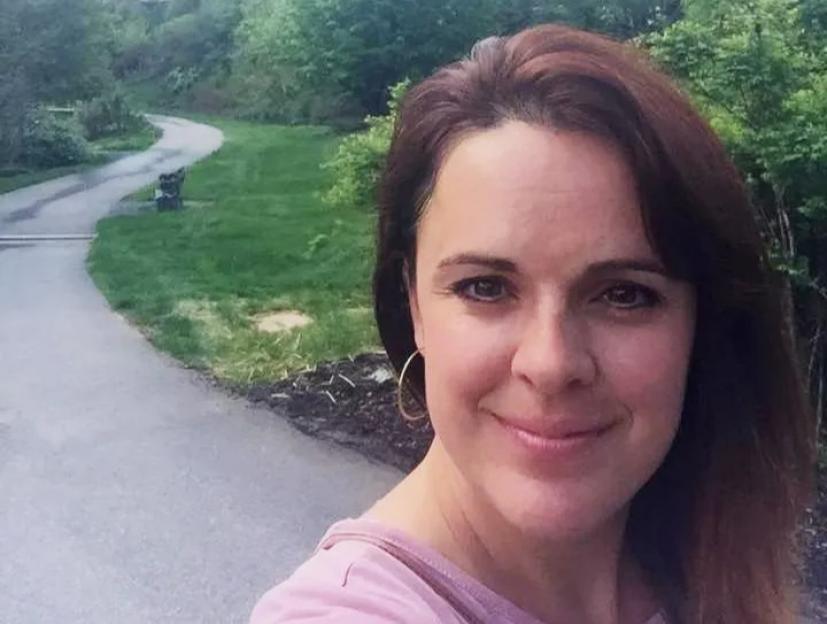 Angela Craig, 43, smiling in a selfie with a winding path and large building in the background.