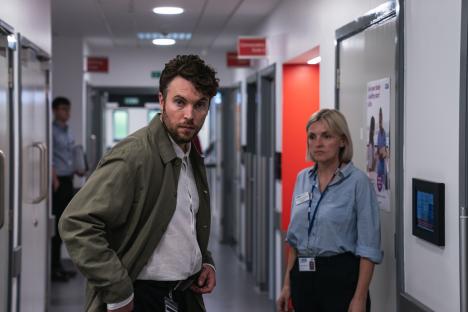 Still from the ITV drama *Malpractice*, showing Tom Hughes as Dr. James Ford and a colleague in a hospital corridor.