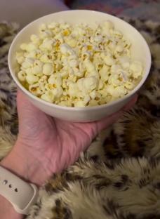 A hand holding a bowl of popcorn.