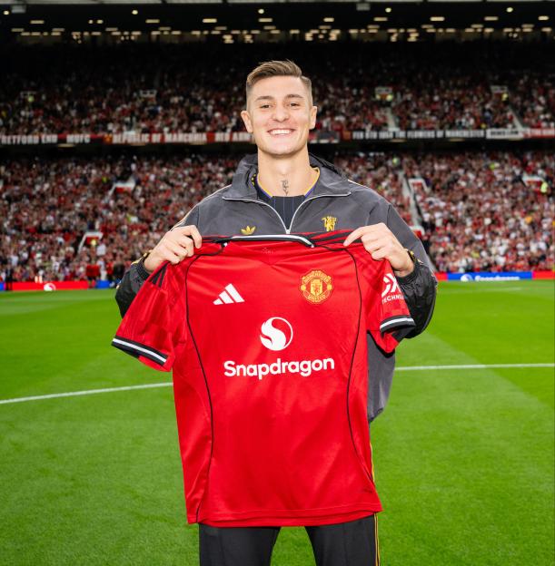 Benjamin Sesko holding a Manchester United jersey at Old Trafford.
