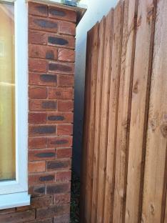 Brick wall and wooden fence separating two properties.
