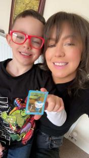 A woman and young boy holding a collectible card.