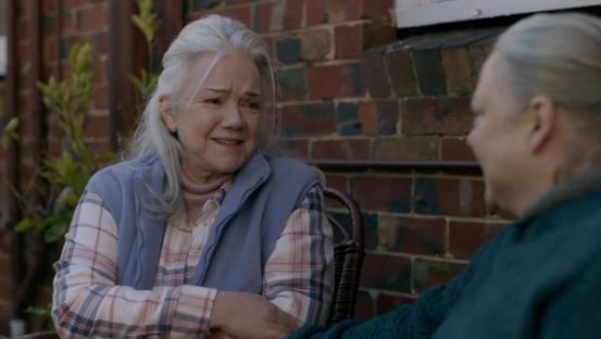 Two elderly women sitting outside, talking.