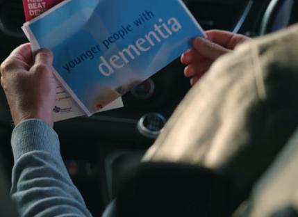 Person reading a pamphlet about younger people with dementia.