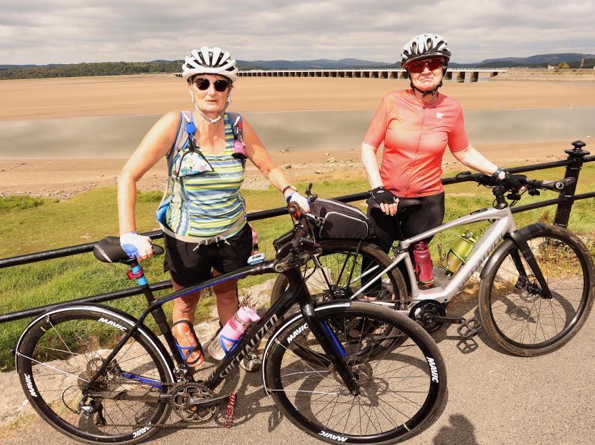 Two cyclists with their bicycles by a seaside.