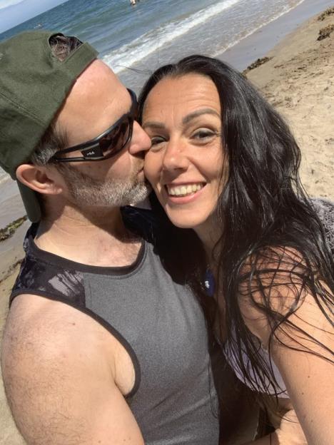 A man kissing a woman on the cheek at the beach.