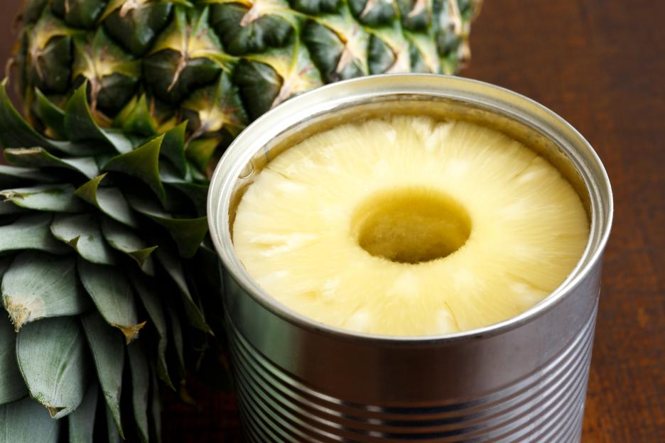 Canned pineapple rings next to a whole pineapple.