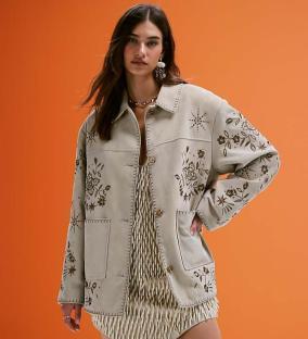 Woman wearing embroidered beige jacket and dress.