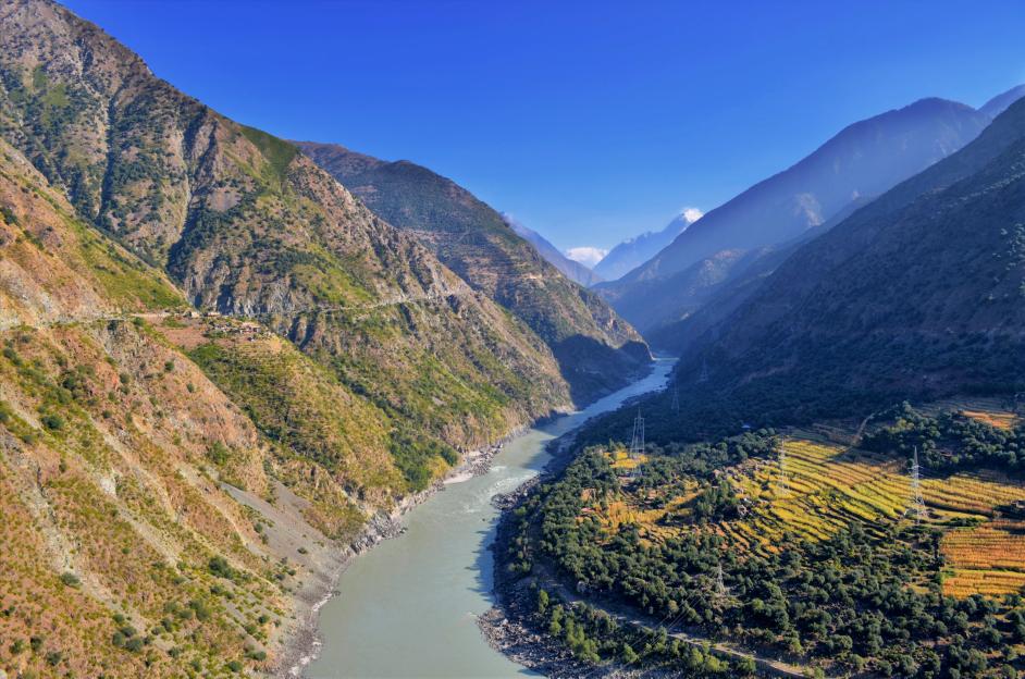 Aerial view of Kohistan, Pakistan, showing a river flowing through a valley between mountains.