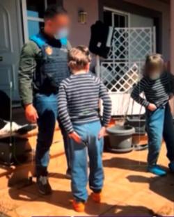 Police officers with three children outside a house.