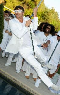 Ashton Kutcher at a White Party, swinging on a chain swing.