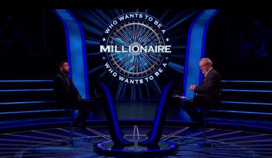 Screenshot of Who Wants to Be a Millionaire set with host and contestant.