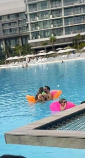 Couple kissing in a pool on inflatable floats, another person in a pink float nearby.