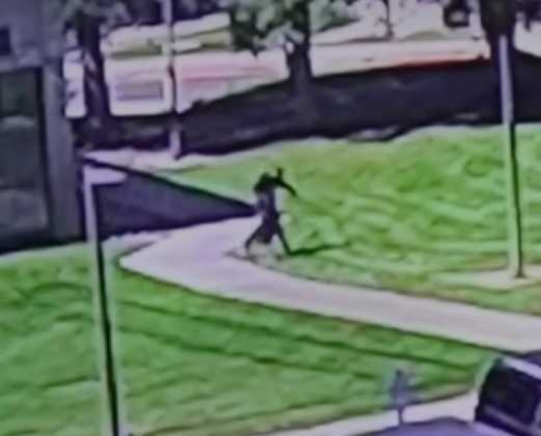 Security camera footage of a person walking on a sidewalk.