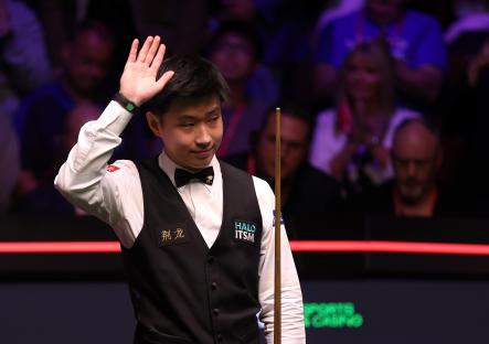 Zhao Xintong of China acknowledges fans at a snooker championship.