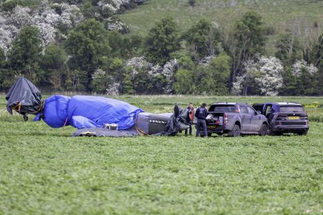 Volunteers guarding a crash-landed 1940s Spitfire in a field.