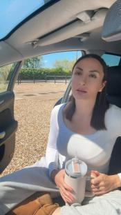 Liana Isadora Van Riel in a car, holding a drink.