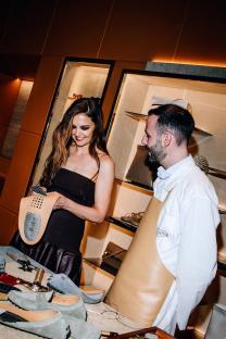Katie Holmes at a Tod's cocktail party, examining a shoe insole with a Tod's artisan.