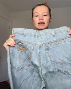 Woman holding up a pair of light wash jeans.