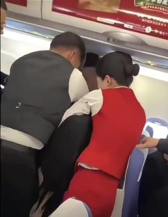 Flight attendants and passengers restraining two fighting female passengers.