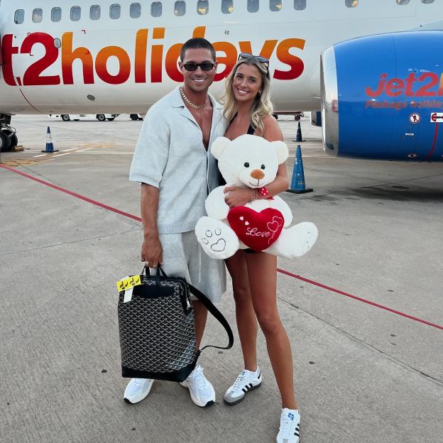 Couple at the airport with a teddy bear.