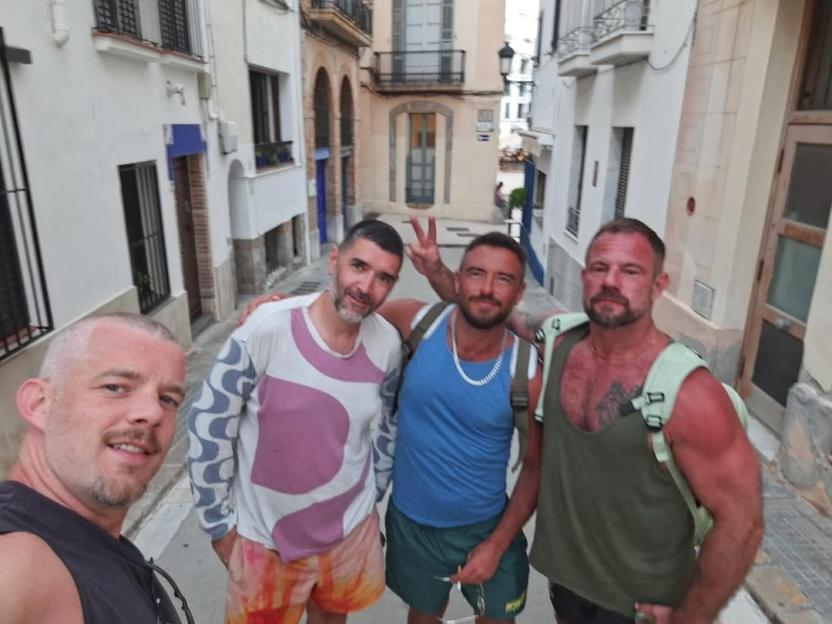 Four men posing for a photo on a street.