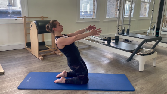 Woman performing a Pilates exercise on her knees.