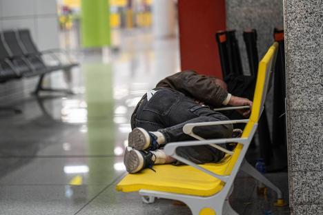 Person sleeping on a bench at an airport.
