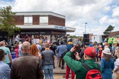 Crowd at an outdoor concert in front of a Sainsbury's Local.