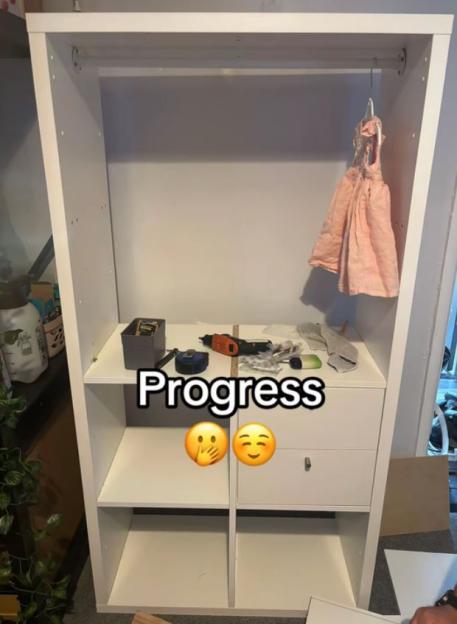 Partially assembled white wardrobe with tools and a pink dress.