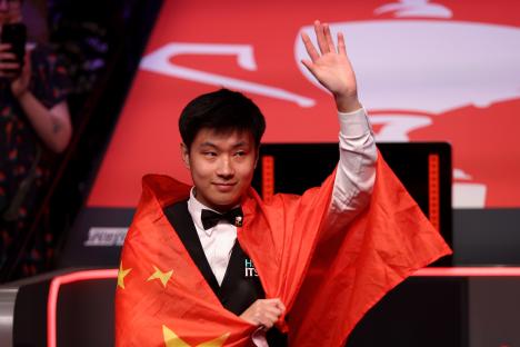 Zhao Xintong of China waves to fans after winning a snooker match.