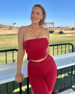 Paige Spiranac in a red outfit at a golf course.