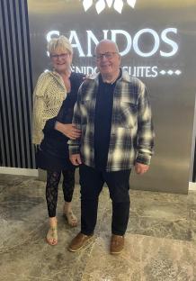 A couple posing in front of a Sandos Suites sign.