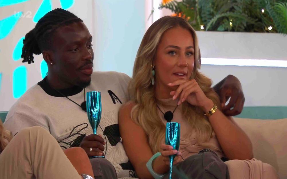 Dejon and Meg from Love Island holding teal champagne glasses.