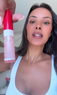 Woman holding a tube of lip gloss.