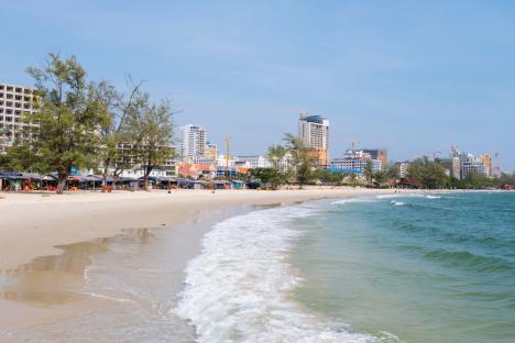 Beach in Sihanoukville, Cambodia, with buildings and construction cranes in the background.