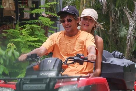Louis Tomlinson and Zara McDermott riding an ATV.
