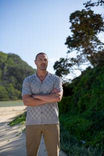 Man standing outdoors with arms crossed.