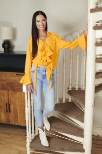 Woman in orange shirt and jeans on a spiral staircase.