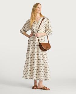 Woman in patterned maxi dress and brown crossbody bag.